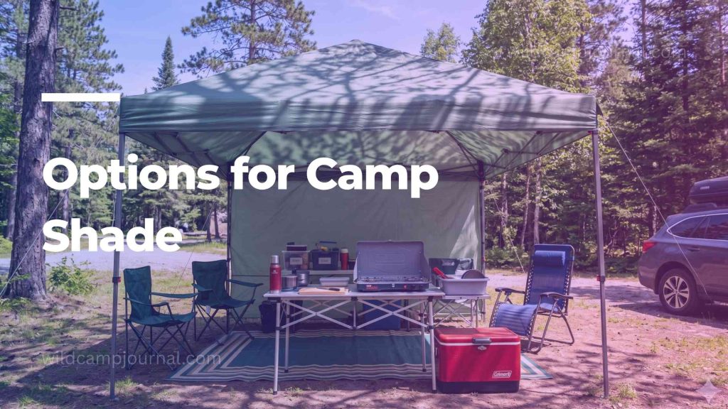 Pop-up canopy shelter set up over a camp kitchen area with folding table stove and chairs at a sunny summer campsite